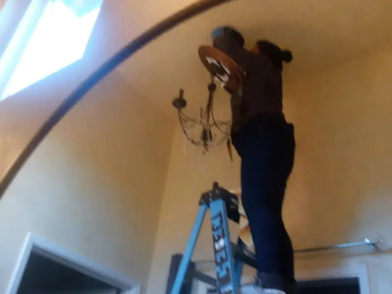 Electrician installing a chandelier in a German Flatts residence